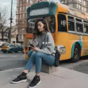 在一辆停在街角的公共汽车旁一位身穿灰色毛衣和蓝色牛仔裤的女性正用智能手机看着什么?她的头发是灰色或绿色颜色的呢?